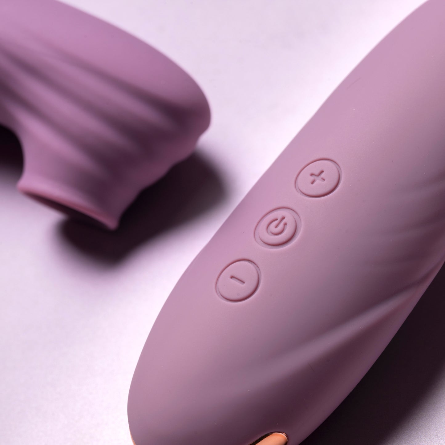 Close-up of pink clitoral suction vibrator buttons on pink surface