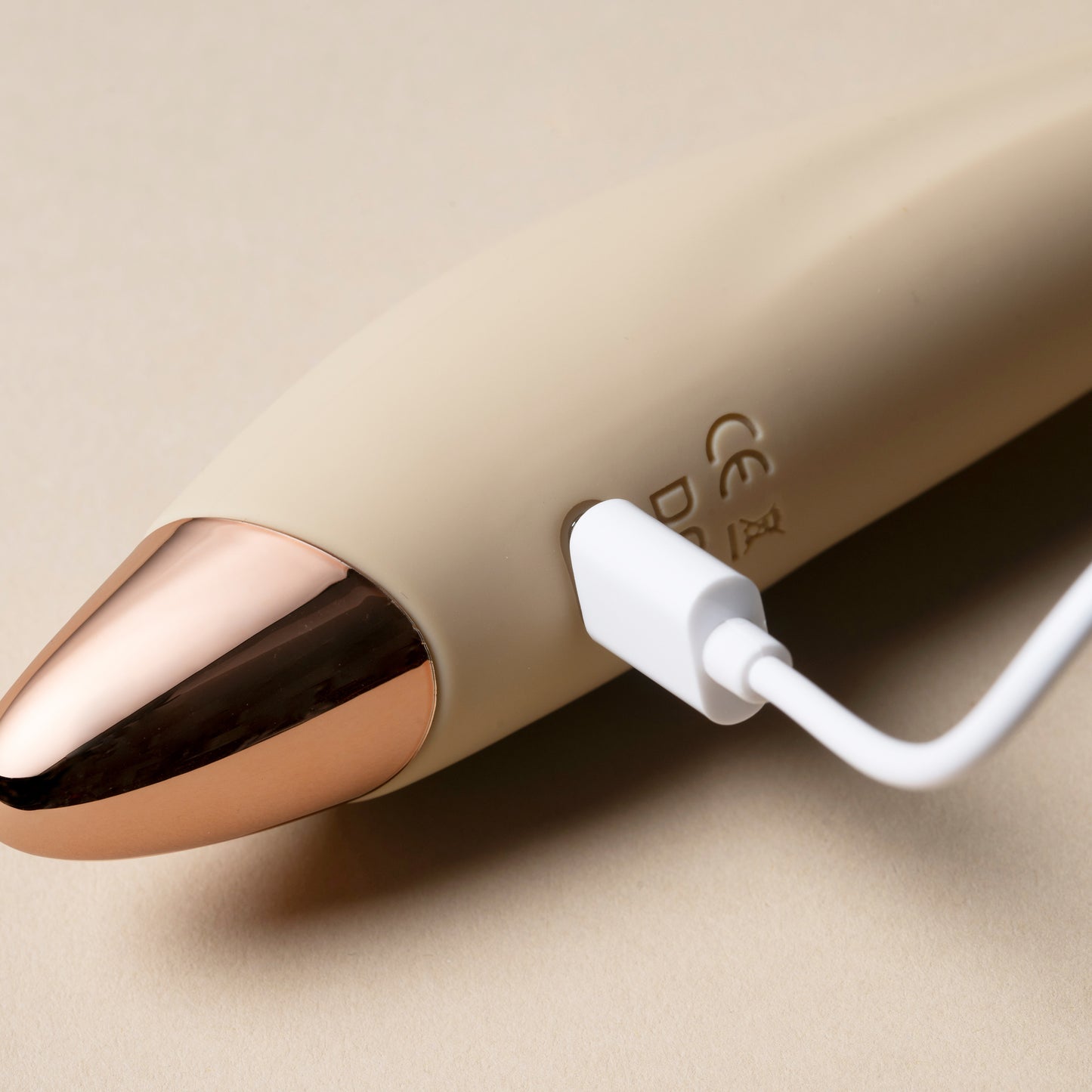 Charging cable inserted into vanilla G-spot vibrator, cream background