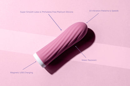 Compact pink bullet vibrator on a pink surface with labeled features: 10 vibration patterns and speeds, magnetic USB charging, water resistance, and body-safe platinum-grade silicone.